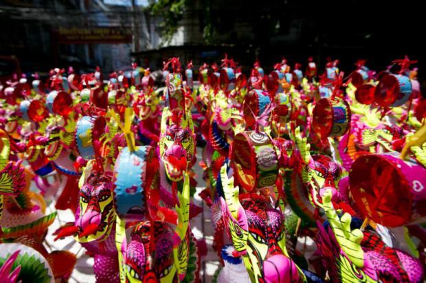 Dense cluster of colorful handmade paper dragon figures in pink, yellow and red tones, festive and vibrant mood